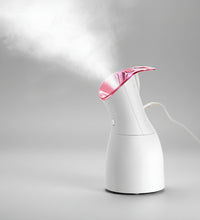 White handheld steamer with pink top emitting steam on a dark background