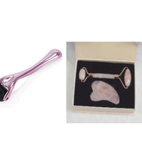 Beauty tool set with pink roller, rose quartz stone, and roller in a box on a white background