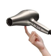 Hand holding a silver hair dryer against a dark background
