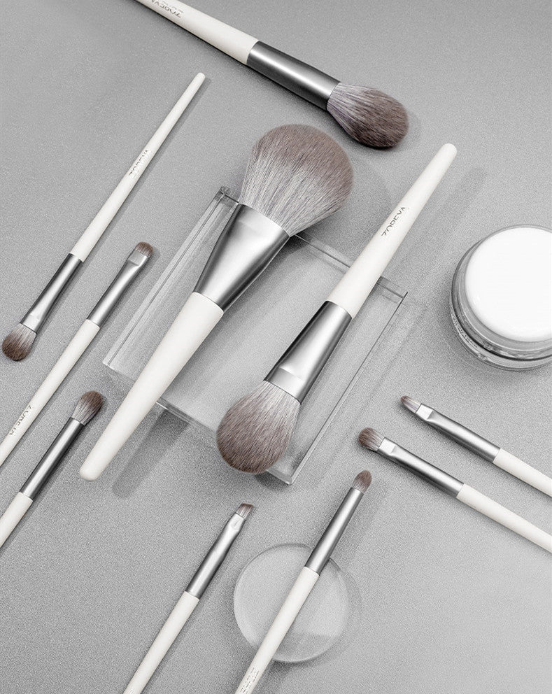 Makeup brushes and a jar of cream on a gray surface