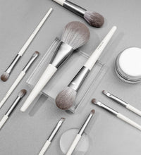 Makeup brushes and a jar of cream on a gray surface