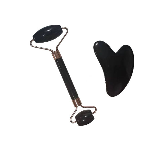 Black facial roller and gua sha tool on a white background
