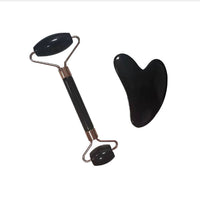 Black facial roller and gua sha tool on a white background