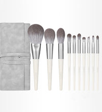 Set of makeup brushes with a gray case on a white background