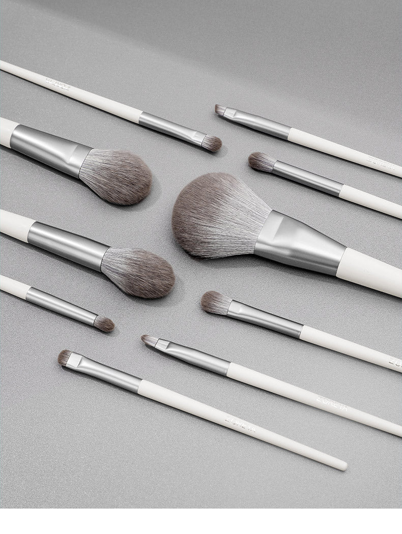 Set of makeup brushes with white and silver handles on a gray background