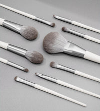 Set of makeup brushes with white and silver handles on a gray background