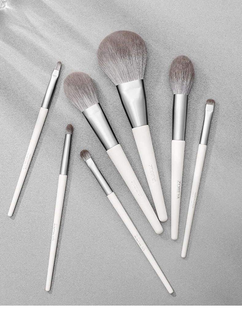 Set of makeup brushes with white handles on a gray background