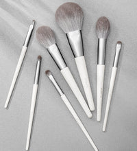 Set of makeup brushes with white handles on a gray background