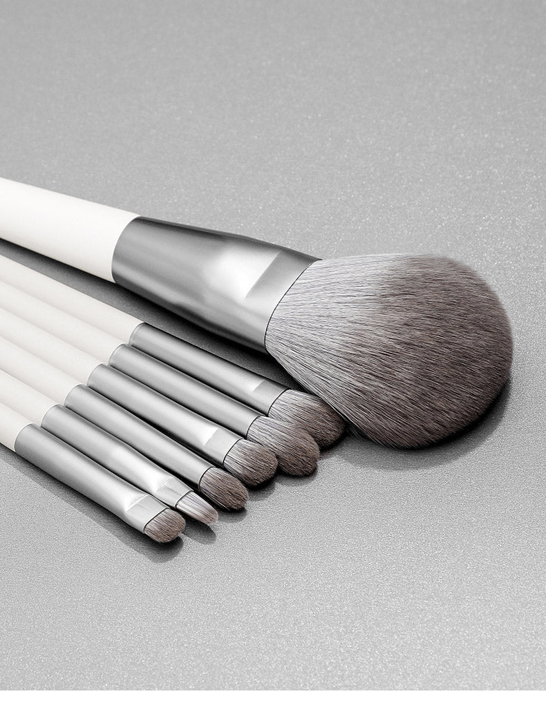 Set of makeup brushes with white handles and silver ferrules on a gray background