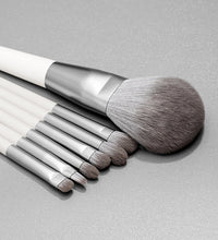 Set of makeup brushes with white handles and silver ferrules on a gray background