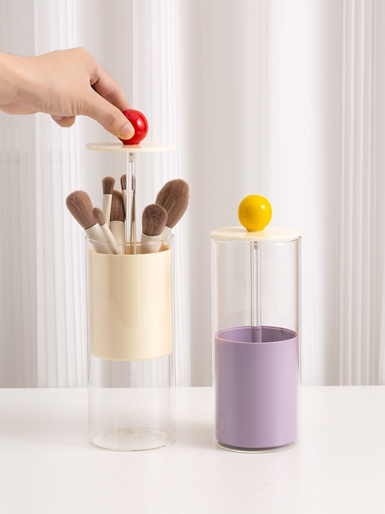 Two cylindrical containers with brushes and a lemon, against a white curtain background.