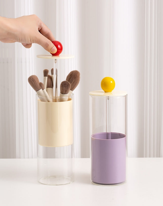 Two cylindrical containers with brushes and a lemon, against a white curtain background.