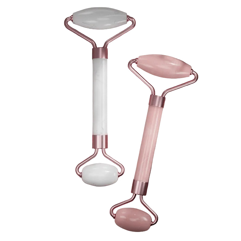 Two facial rollers with jade and pink handles on a textured surface
