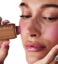 Woman applying Olibolla lipstick to her lips with a close-up view.