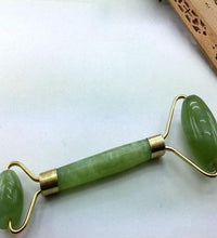 Green jade roller with gold accents on a white surface