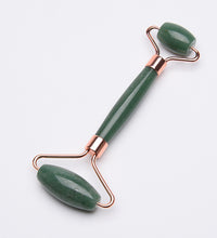 Green jade roller with rose gold accents on a white background