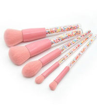 Set of pink makeup brushes with colorful handles on a white background
