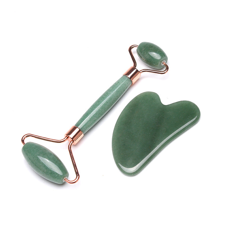 Green jade roller and gua sha tool on a white background