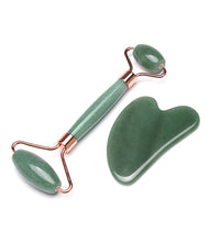 Green jade roller and gua sha tool on a white background