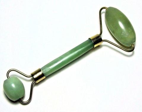 Green jade facial roller on a white background
