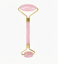 Pink facial roller with gold accents on a white background
