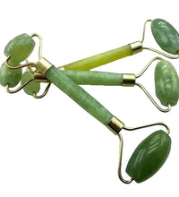 Green jade rollers with gold accents on a white background