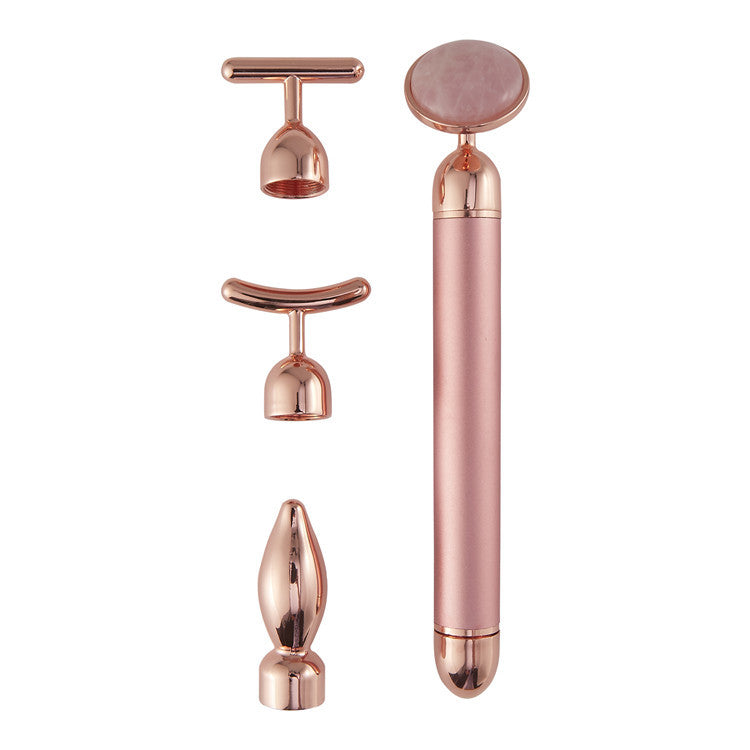 Rose gold facial massager with multiple attachments on a white background