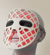 White mask with red grid pattern on a neutral background
