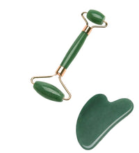 Green facial roller and gua sha tool on a light green platform with a decorative background.