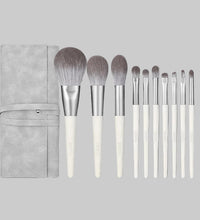 Set of makeup brushes with a gray case on a white background