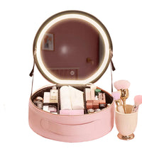 Pink travel vanity case set up on a desk next to makeup brushes and skincare