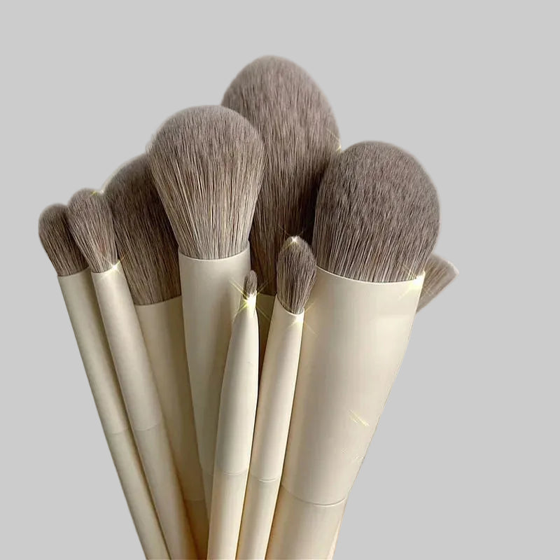 Set of makeup brushes with beige handles and brown bristles on a light gray background