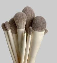 Set of makeup brushes with beige handles and brown bristles on a light gray background