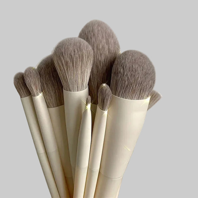 Set of makeup brushes with beige handles and brown bristles on a light gray background