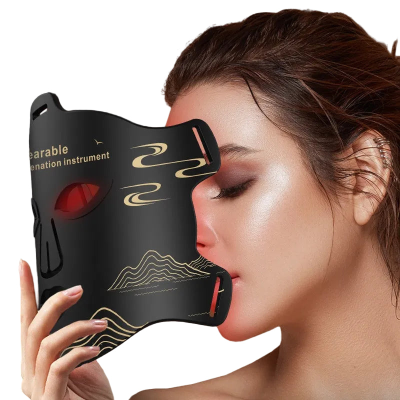Woman holding a black face mask with red lights and gold designs against a dark background