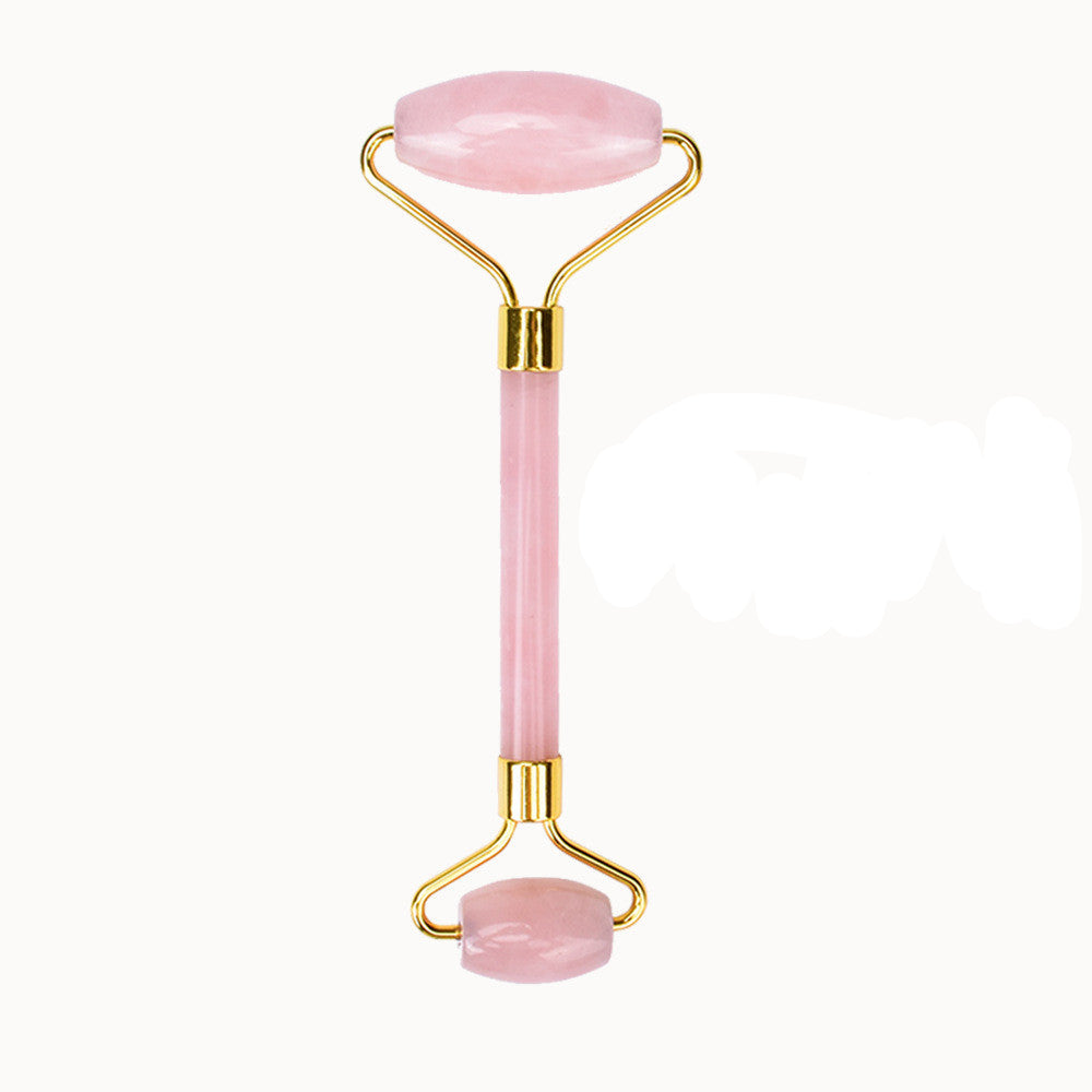 Pink facial roller with gold accents on a white background