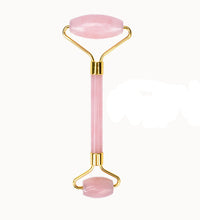 Pink facial roller with gold accents on a white background