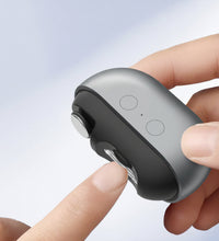 Multifunctional electric nail clippers being held with a hand, on a light blue background.