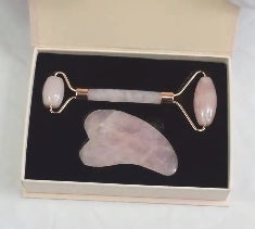 Rose quartz roller and gua sha tool in a black box on a white background