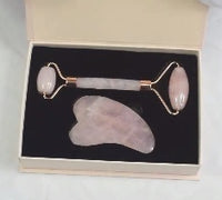 Rose quartz roller and gua sha tool in a black box on a white background