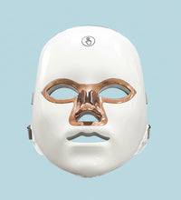 White facial mask with bronze accents on a white background